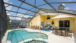 Un área de piscina exterior techada con sillas de descanso y una mesa.