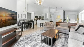 Una sala de estar moderna con un televisor de pantalla plana grande, una mesa de centro de madera y un sofá gris.