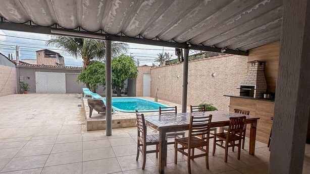 An outdoor patio area with a pool, a dining table with chairs, and a barbecue grill.