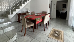 A dining area with a round table, chairs, and a staircase leading to another room.