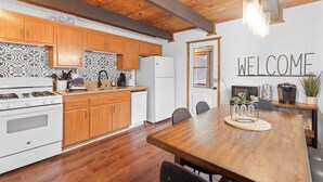 Eine Küche mit Holzausbau, einem weißen Kühlschrank und einem Esstisch mit Stühlen.