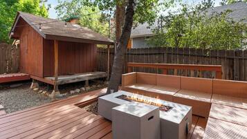 A wooden deck with a built-in fire pit and a wicker sofa.