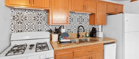 A kitchen with wooden cabinets, a white stove, a sink, and a dishwasher.