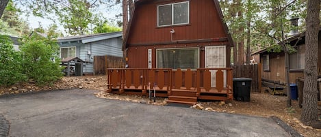 A two-story wooden cabin with a porch, a small deck, and a garage.