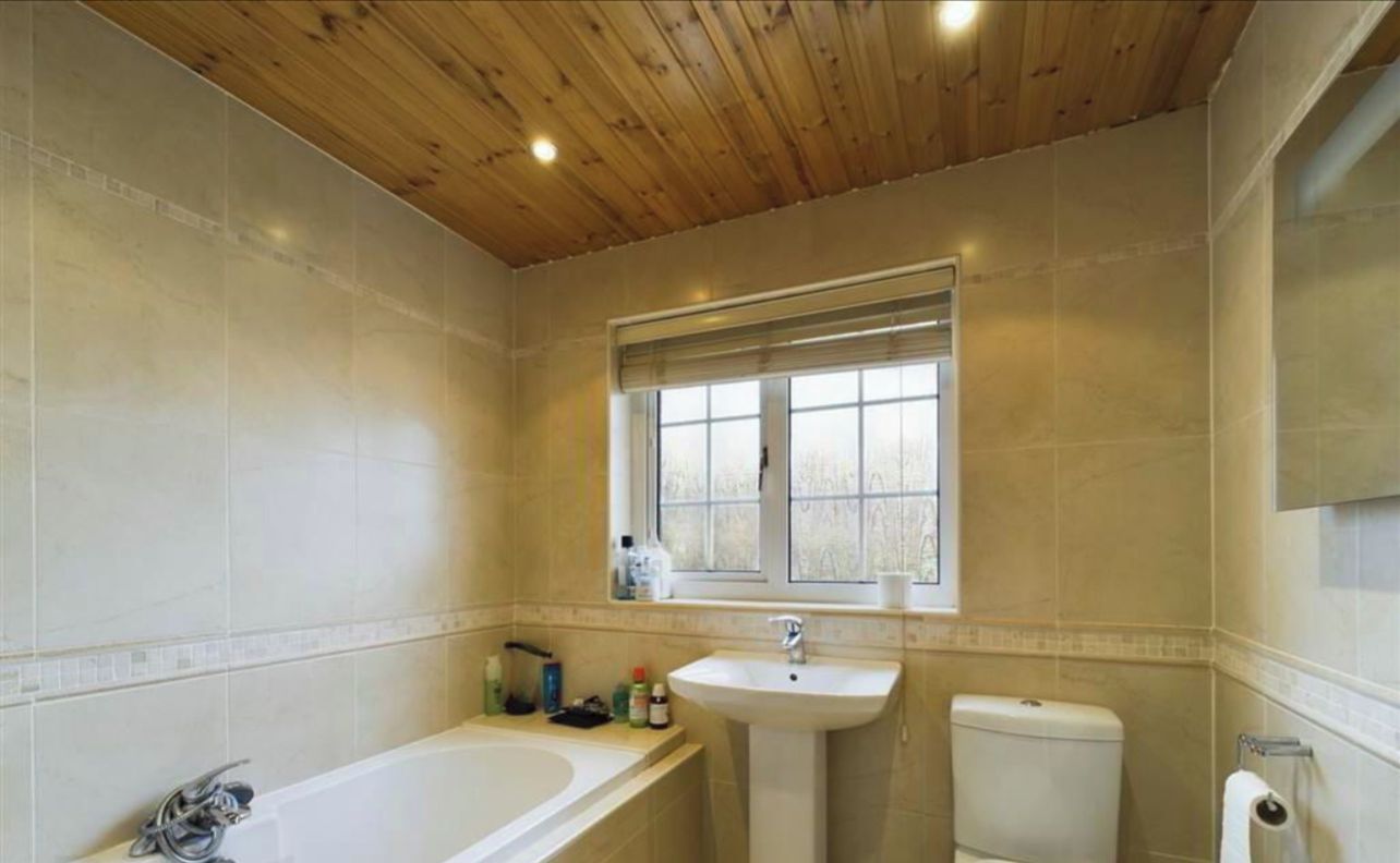 Un baño con techo de madera, una bañera, un lavabo y un inodoro.