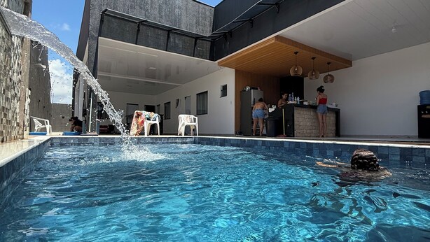 A swimming pool with clear blue water, surrounded by a modern building with a flat roof and large windows. - MC Style house in Salinas, PA, 8 beds and 4 suites (Salinópolis)