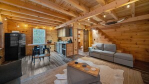 Interior acogedor de una cabaña con comedor, cocina y sofá.