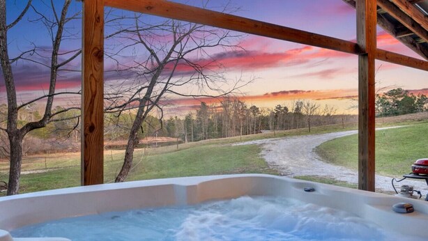 Un jacuzzi con vistas a un paisaje rural y al atardecer.