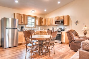 Una cocina con armarios de madera, un refrigerador de acero inoxidable, un microondas y una mesa de comedor con sillas.