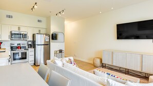 A modern kitchen with white cabinets, stainless steel appliances, and a dining area with a white table and sofa. - Steps to Beach, Heated Pool steps from condo! (Santa Rosa Beach)