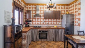 Een functionele keuken met een inbouwoven, een magnetron, een gasfornuis en een koelkast.