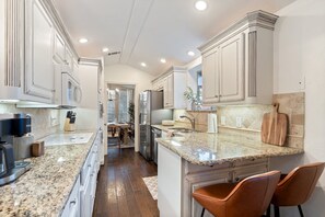 A modern kitchen with granite countertops, stainless steel appliances, and white cabinetry. - Lone Star Retreat - Game Room - Heated Pool & Spa (Carrollton)