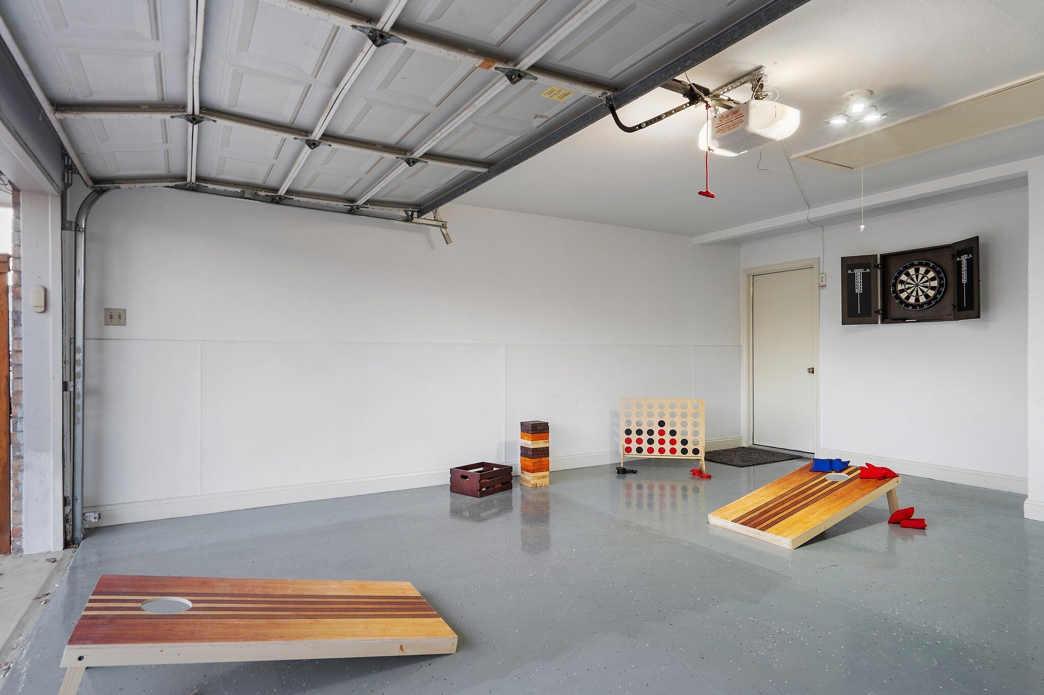 Ruime kamer met een betonnen vloer, een houten hellingbaan, een dartbord en een klok aan de muur.