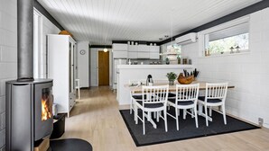 A modern kitchen with white cabinetry, a central island, and a wood-burning stove. - 2 bedroom beautiful home in Jerup (Jerup)