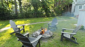 En baghave med bålsted omgivet af Adirondack-stole.