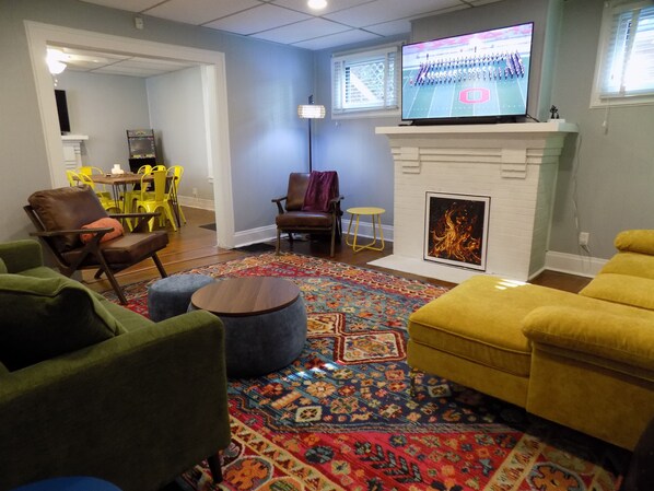 A living room with a fireplace, a television, and a colorful rug. - Lady Pilot, Old North Columbus - Lovely 3-bedroom home, steps to OSU! (Columbus)