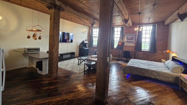 A spacious room with a large bed, a desk with a computer, and a dining area.
