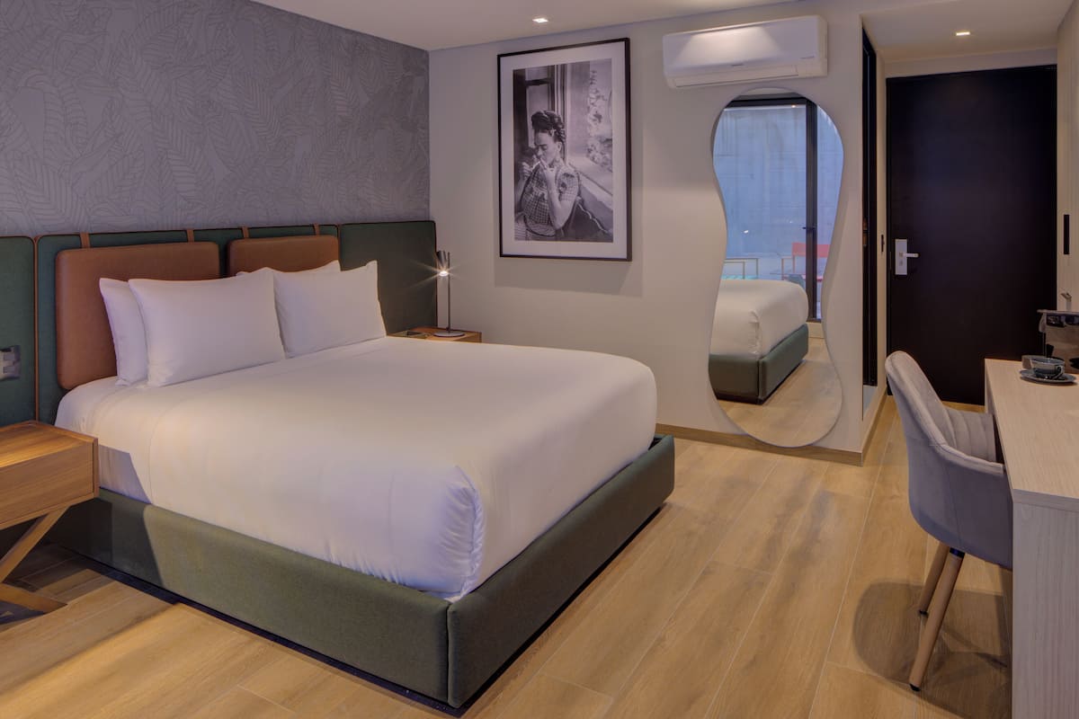 Una habitación de hotel moderna con una cama grande, un escritorio y un espejo.