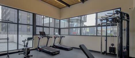 Een sportschool met loopbanden, een bank en krachtapparaten.
