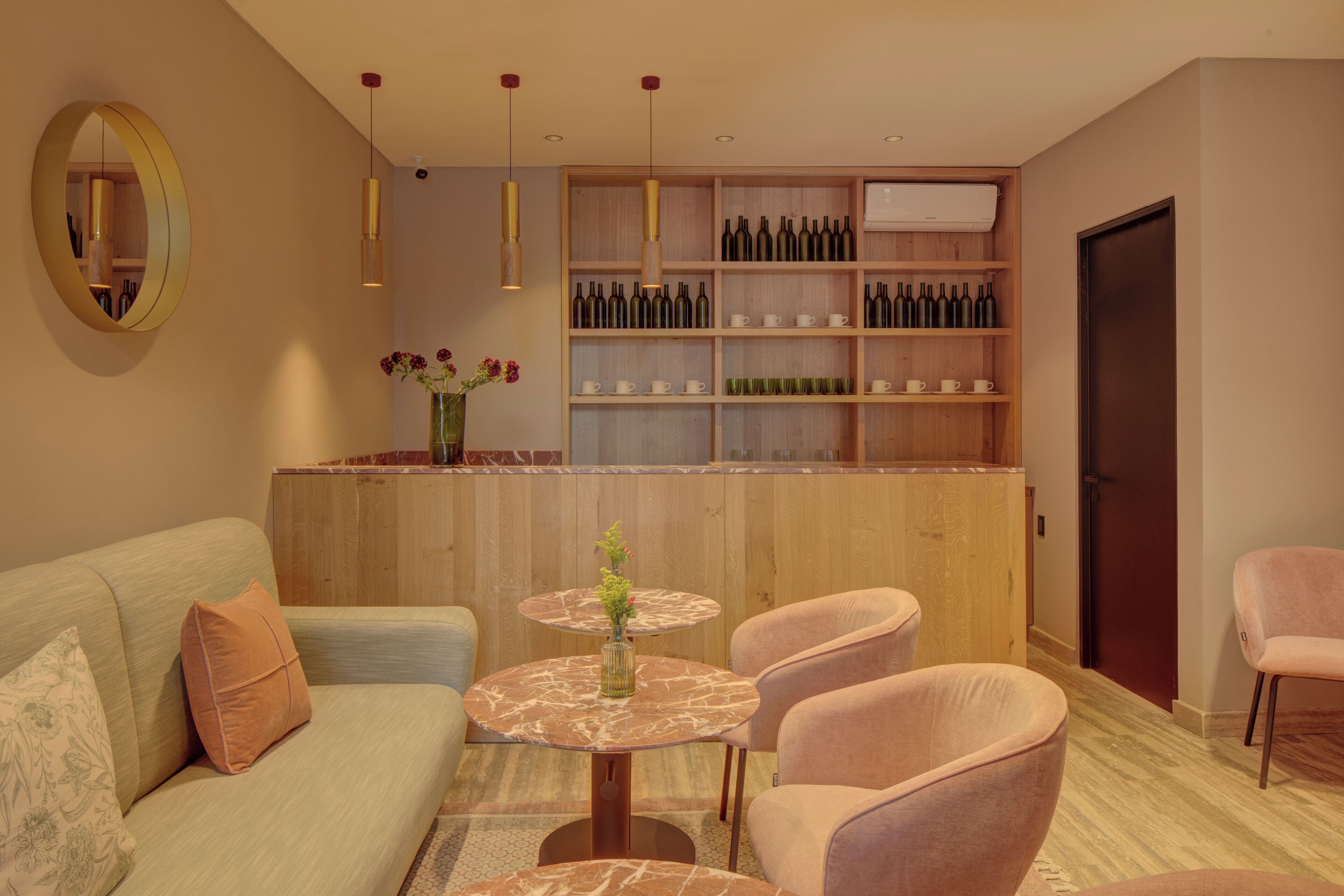 A modern living room with a sofa, two round tables, and a bar area with shelves of wine bottles.