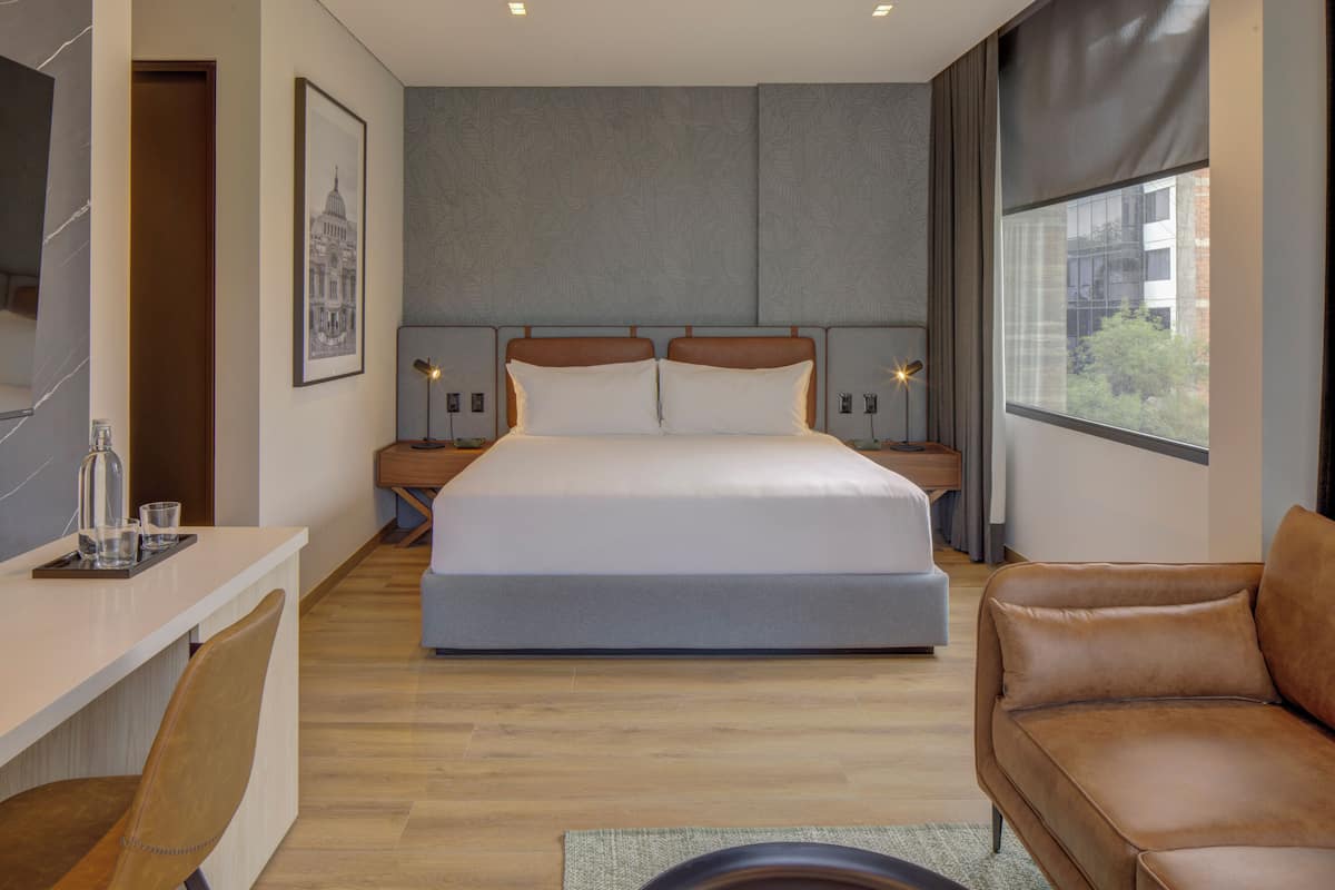 Una habitación de hotel moderna con una cama grande, un escritorio y un sofá de cuero.