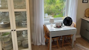 A dining area with a table, chairs, a lamp, and a view of greenery outside. - Fabulous 4-bedroom villa with AC in Møre og Romsdal, boat available (Møre og Romsdal)
