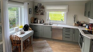 A modern kitchen with a dining area, featuring a window with a view of greenery, a coffee maker, and various kitchen utensils. - Fabulous 4-bedroom villa with AC in Møre og Romsdal, boat available (Møre og Romsdal)