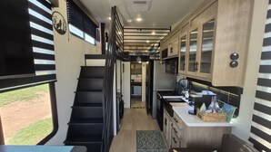 Interni compatti di un camper, con cucina, zona pranzo e una scala.