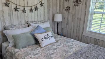 Een slaapkamer met een bed, decoratieve wanddecoraties, een lamp en een raam met uitzicht.
