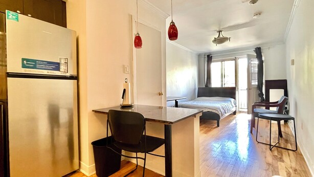 A compact room with a kitchenette, a bed, a desk, and a chair. - Steps from McGill: A Bright, Central Apartment for Your Summer Adventure (Montréal)