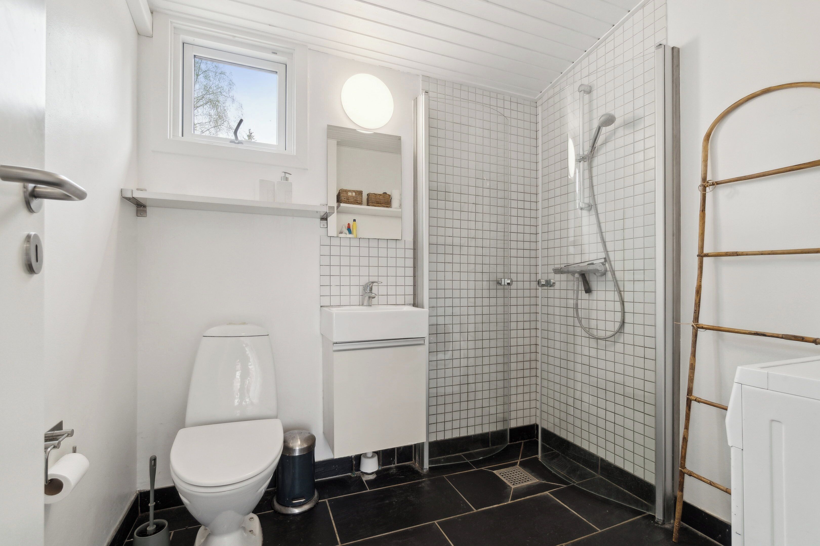 A bathroom with a toilet, sink, mirror, and shower.