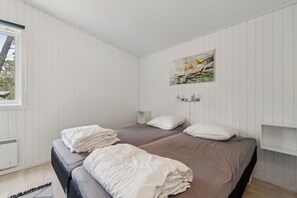 A room with two beds, a window, and a painting on the wall.