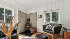 A cozy living room with a fireplace, a sofa, a table, and a vase with dried plants.