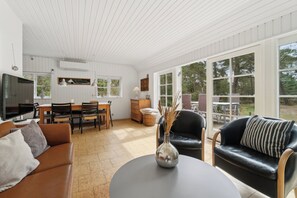 A spacious living area with a dining table, sofas, and a TV.