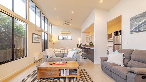 A modern living room with a sofa, a coffee table, and a dining area.