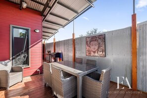 A covered patio with wicker furniture, a table, and a grill.