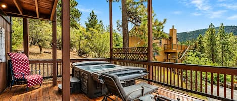 A wooden deck with a hot tub, a red polka dot chair, and a bench.