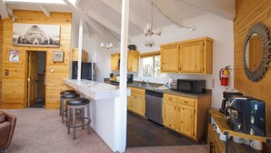 Eine gemütliche Küchenzeile im Chalet-Stil mit Holzausbau, einer Bar und einem großen Spiegel.