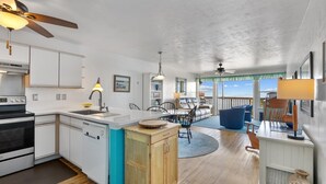 Cozinha moderna com ilha central, área de jantar com vista e sala de estar com ventilador de teto.