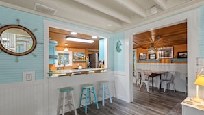 A kitchen with a wooden island, bar stools, and a view into the dining area.