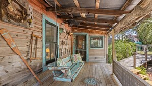 A wooden porch with a swing, rustic decor, and a view of the outdoors.