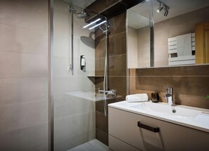 A modern bathroom with a glass shower enclosure, a white sink, and a mirror above the sink.