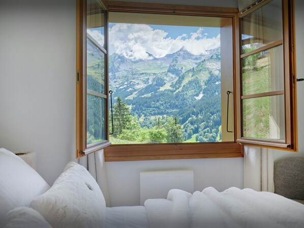 A bedroom with a large window offering a mountain view.