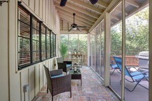 A covered patio area with wicker furniture, a ceiling fan, and a view of the outdoors.