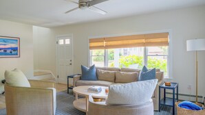 A living room with a beige sofa, two armchairs, a coffee table, and a floor lamp.