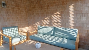 A room with a wooden wall, a light blue sofa, and a wooden chair.