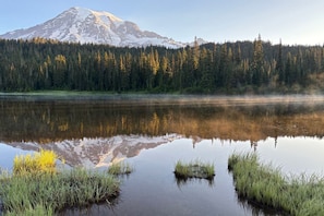 Una montaña, bosque y lago tranquilo con reflejos.