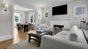 A modern living room with a fireplace, a dining area, and a TV mounted on the wall.