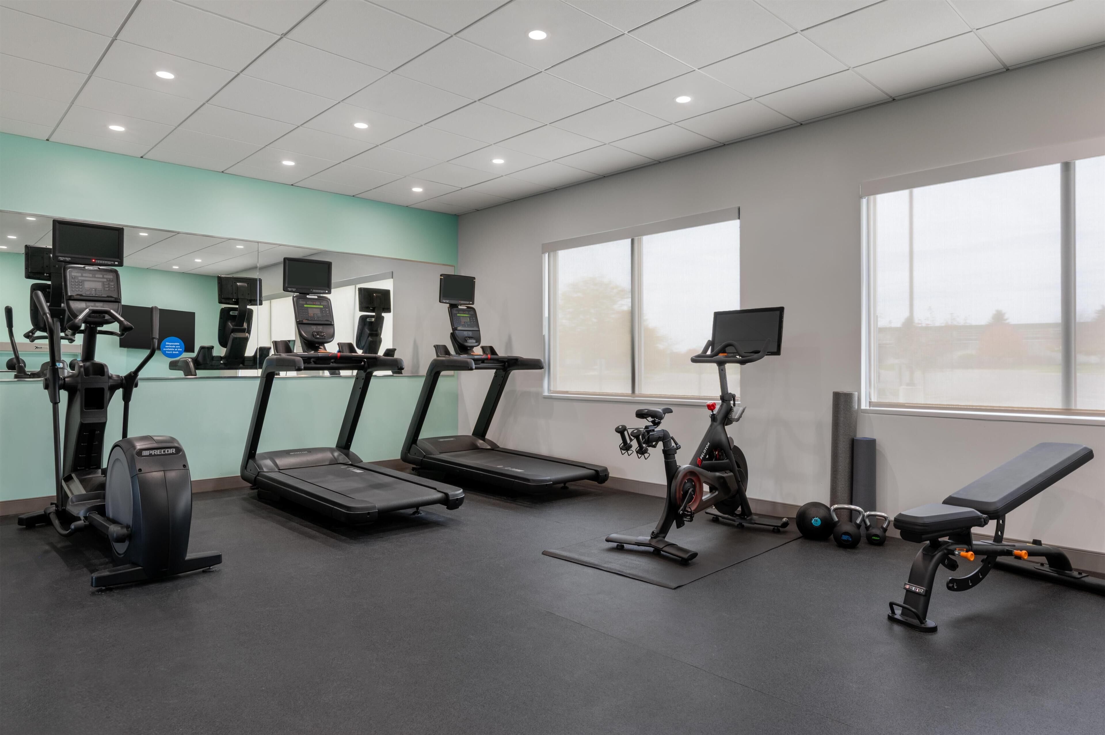 A gym with treadmills, an elliptical, a stationary bike, and a bench.
