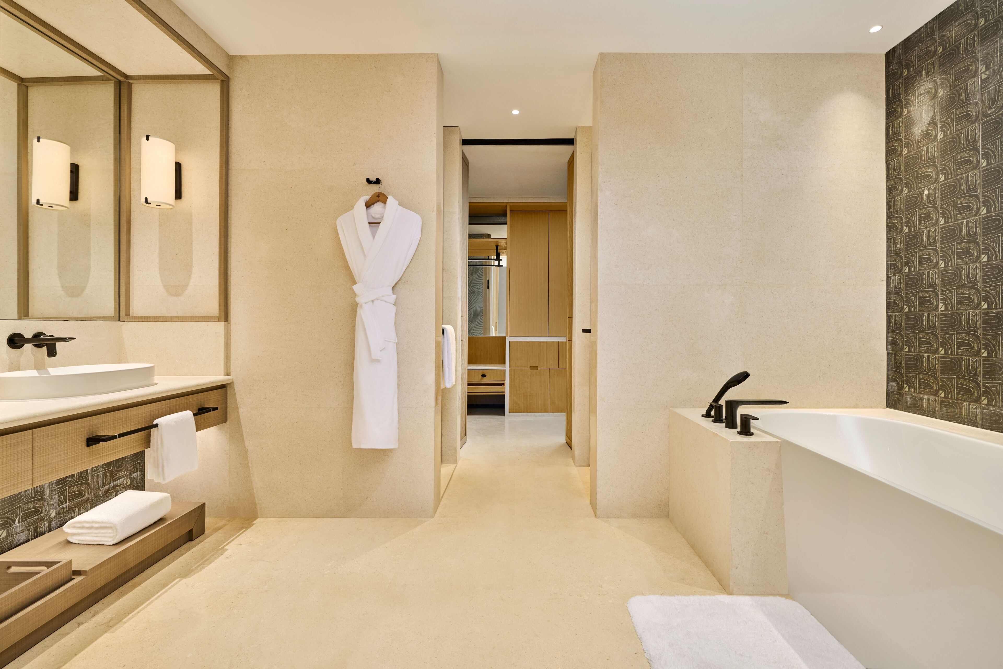 Un baño moderno con un espejo grande, una bañera y un tocador con lavamanos.